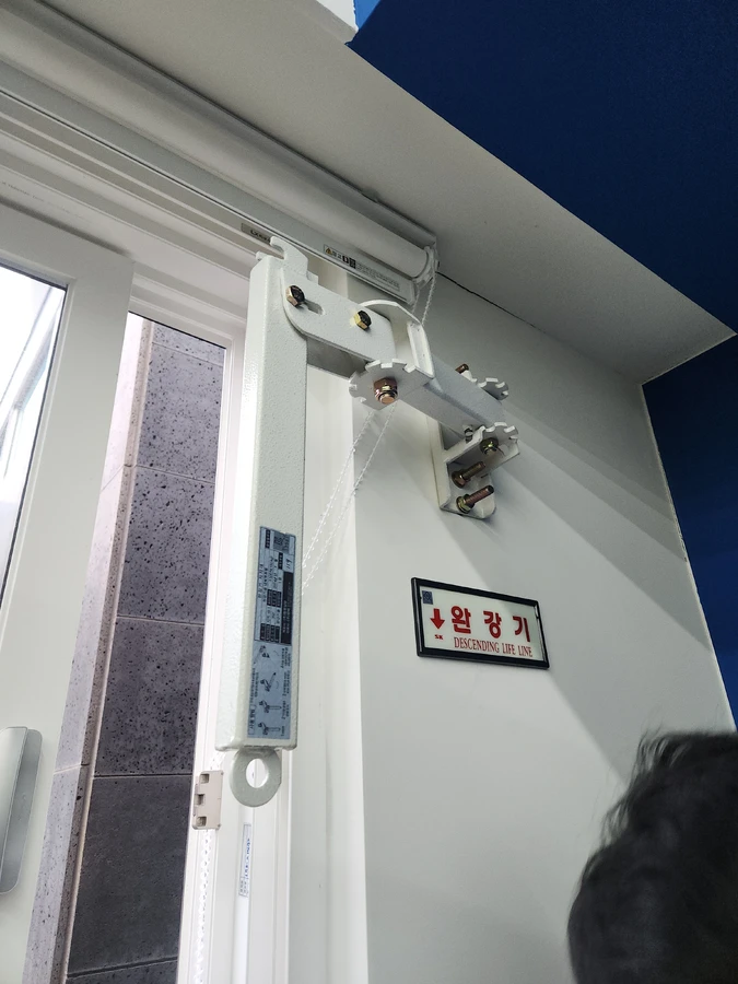 창 옆 브라켓 지지대와 완강기 표지판 근접
